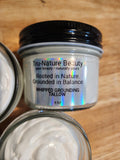 A jar of Tru-Nature Beauty Whipped Grounding Tallow cream on a wooden surface, with other open jars showing the white cream partially visible.