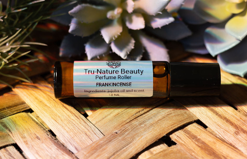Tru-Nature Beauty Frankincense perfume roller bottle on a woven surface with plants in the background