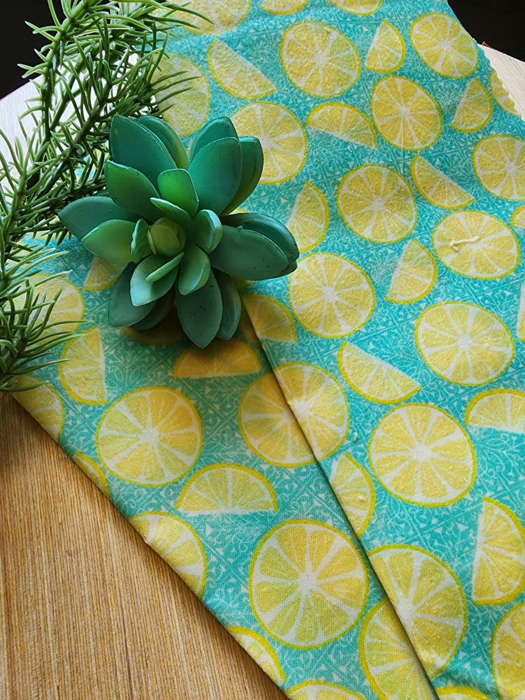Green succulent on a lemon-patterned fabric with a wooden surface underneath