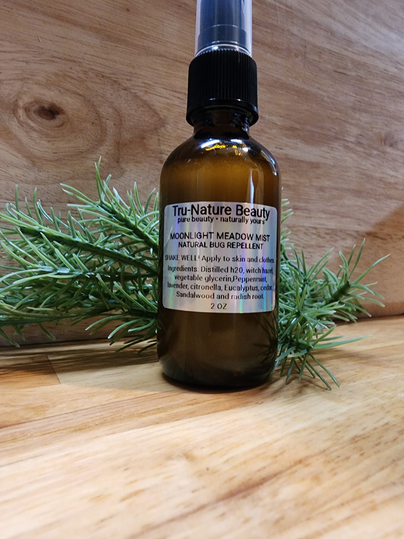 Bottle of Tru-Nature Beauty natural bug repellent on a wooden surface with greenery.