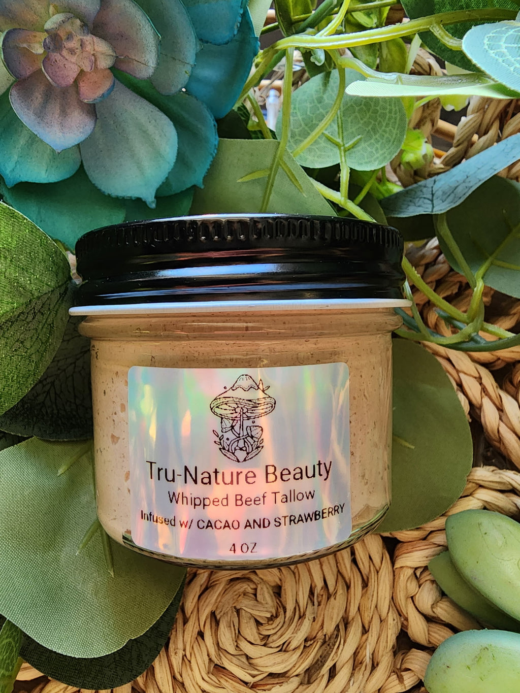Jar of Tru-Nature Beauty whipped beef tallow product with a label, surrounded by greenery.