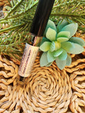 Roll-up bottle of eye serum with a succulent plant on a woven mat