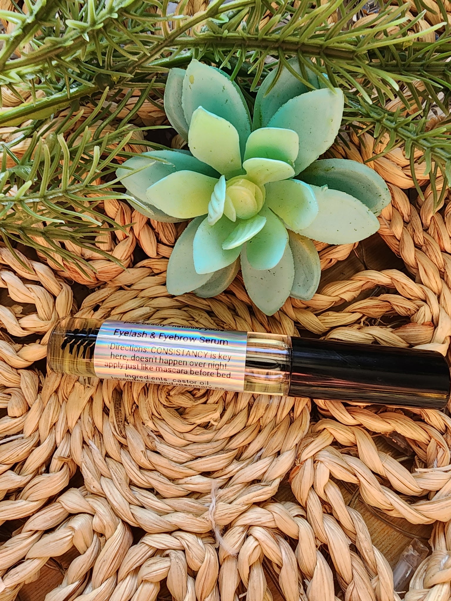 Small bottle of perfume with a green succulent on a woven surface