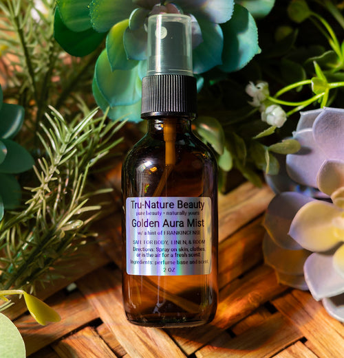 Bottle of Tru-Nature Beauty Golden Aura Mist surrounded by plants on a wooden surface