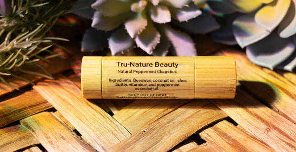 Tru-Nature Beauty natural peppermint chapstick on a wooden surface with plants in the background