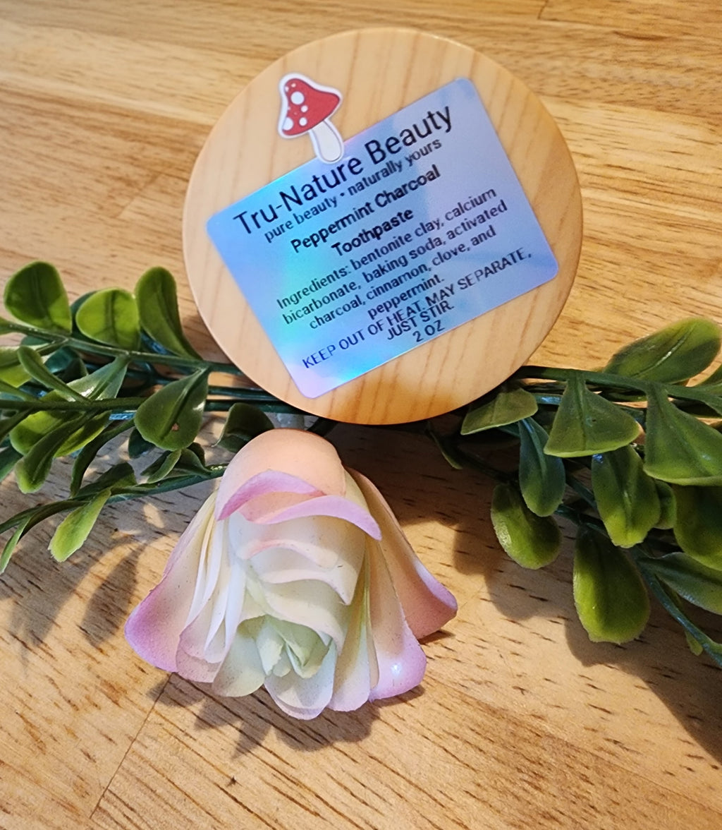 Toothpaste with a wooden cap labeled 'Tru Nature Beauty' on a wooden surface with green leaves.