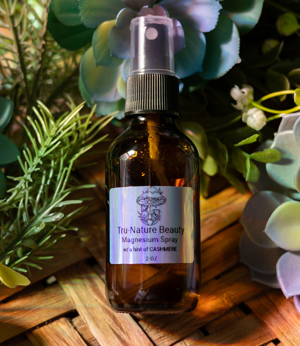 Brown spray bottle labeled 'Tru-Nature Beauty' on a wooden surface with greenery in the background