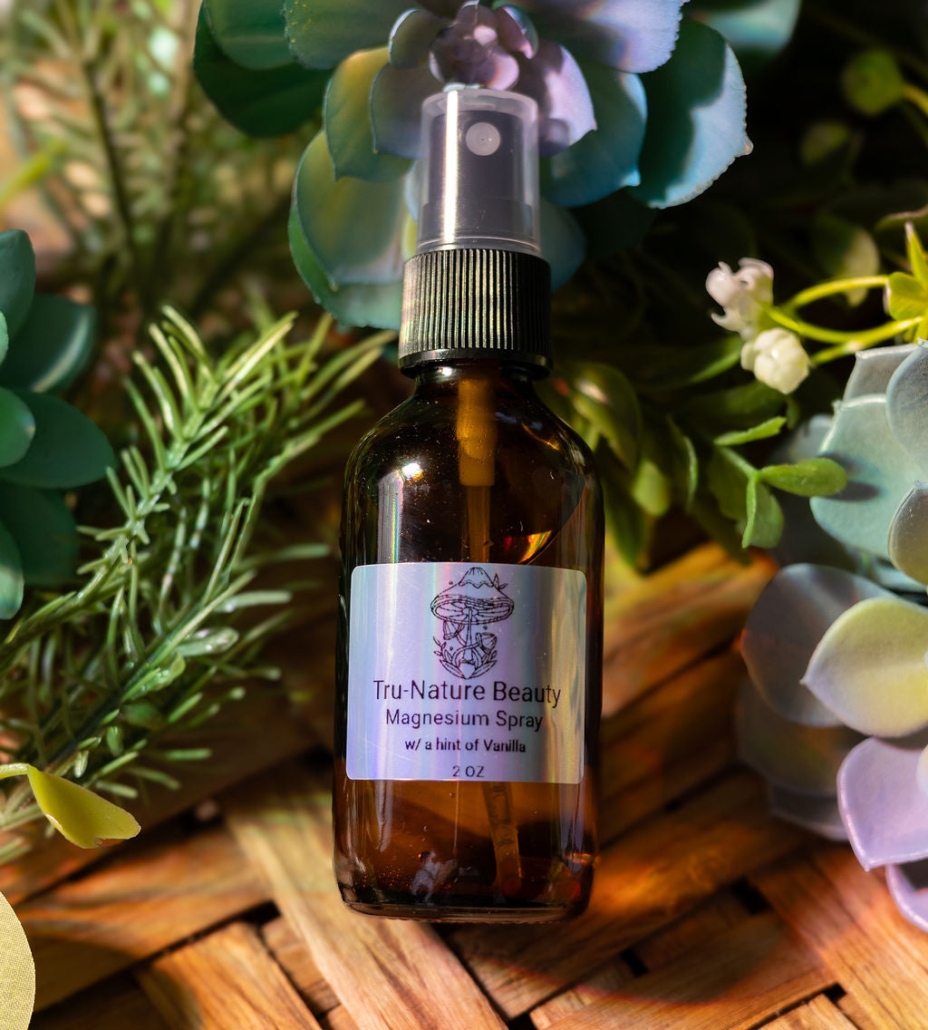Bottle of Tru Nature Beauty magnesium spray surrounded by greenery on a wooden surface