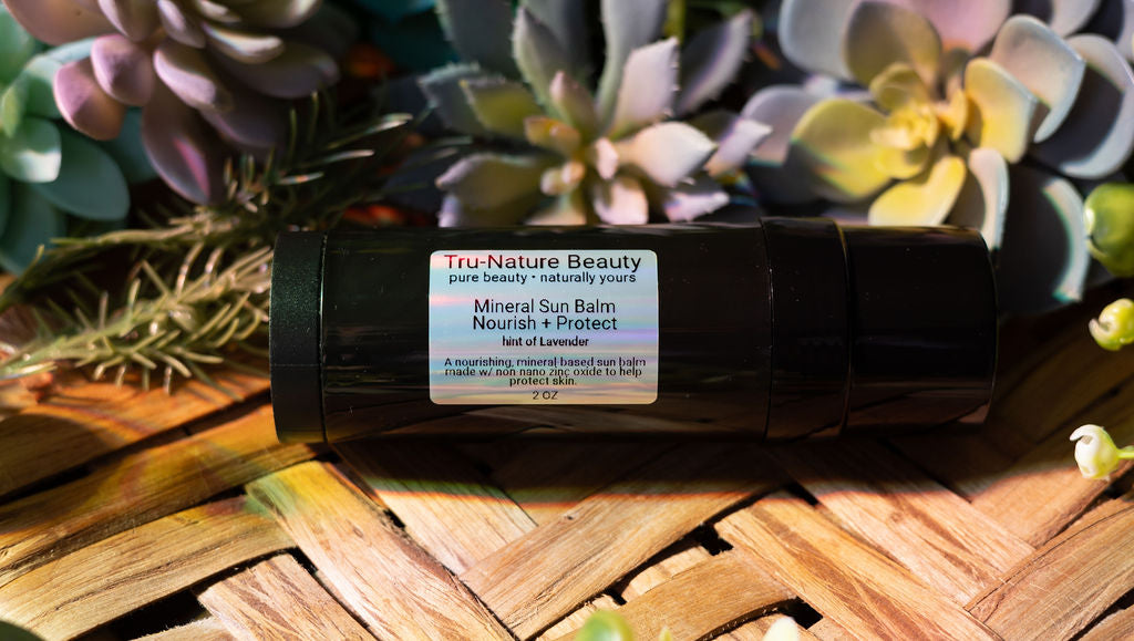 Tru-Nature Beauty mineral sun balm on a woven surface with plants in the background
